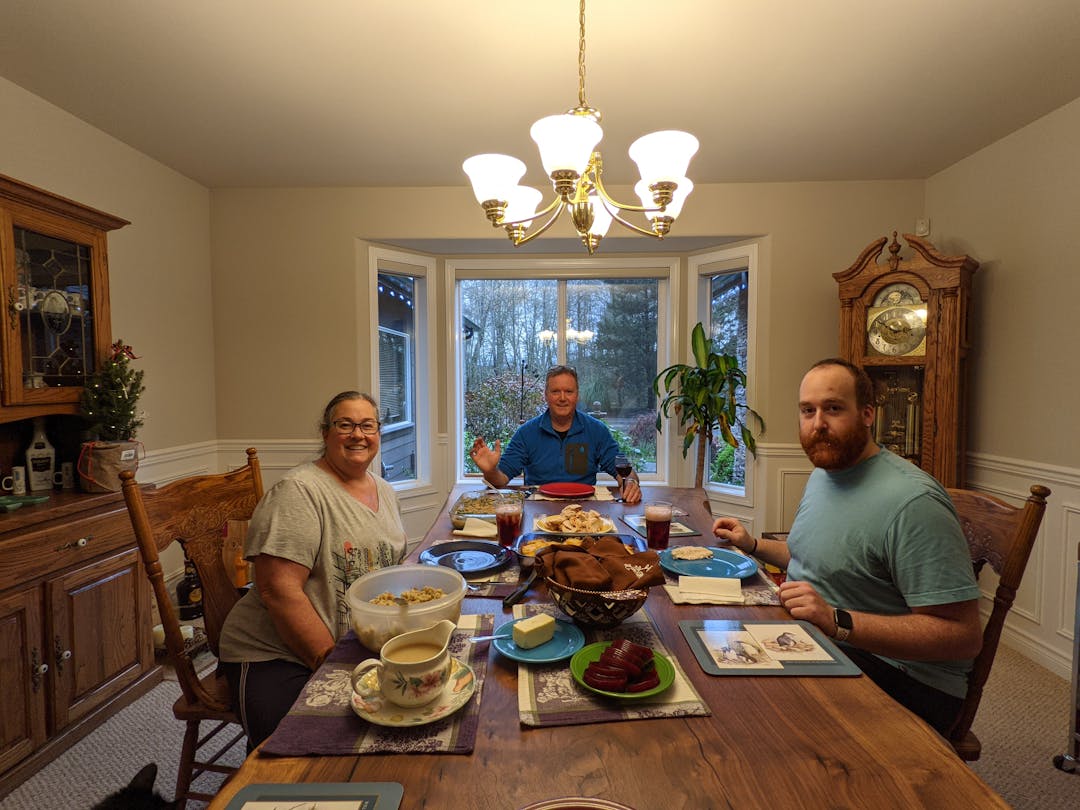 My mom, dad, and brother sitting around the dinner table with food spread across the table